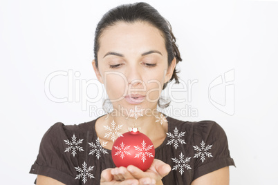 Frau pustet Schneeflocken über eine Glaskugel