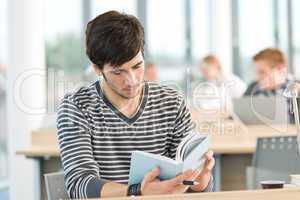 Young male student read book in classroom