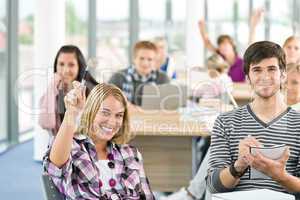 High school student raising hands in classroom