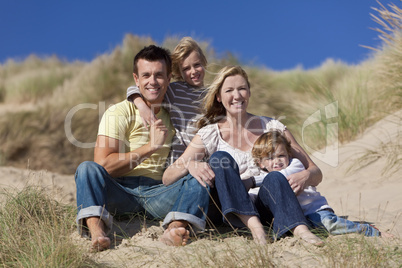 Mother, Father and Two Boys Sitting Having Fun At Beach