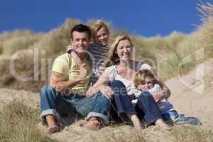 Mother, Father and Two Boys Sitting Having Fun At Beach