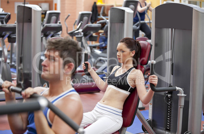 couple using shoulder press in a fitness centre