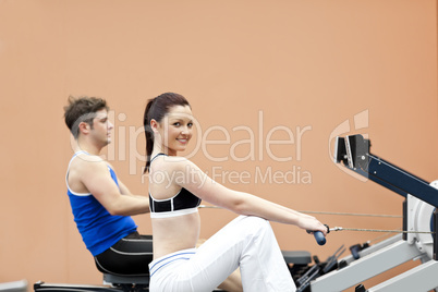 people using a rower in a sport centre