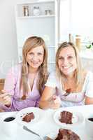 two women eating a chocolate cake