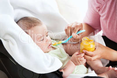 mother giving carrot puree to her baby