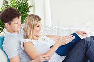 couple browsing a book lying on the sofa