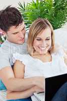 couple with laptop lying on the sofa