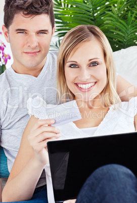couple with laptop laying on sofa