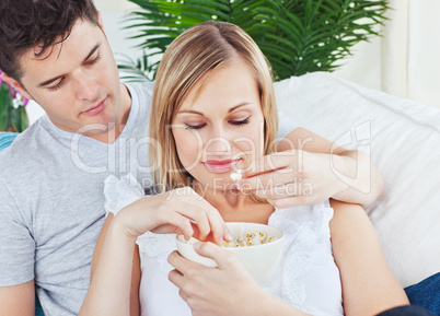 couple relaxing on the sofa and eating pop-corn