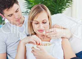 couple relaxing on the sofa and eating pop-corn