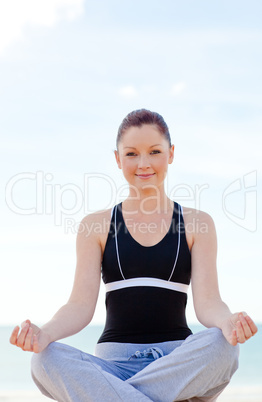 woman doing yoga exercises sitting on the beach