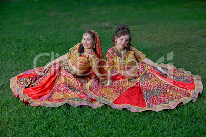 young indian smiling girls sit on grass