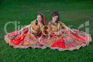 young indian smiling girls sit on grass