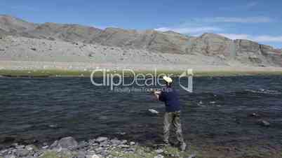Fisherman with spinning catching fish in Khovd river