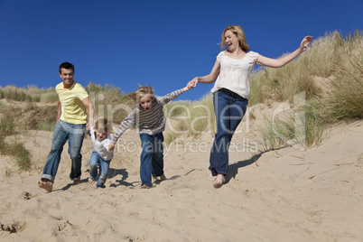 Mother, Father and Two Boys Running Having Fun At Beach