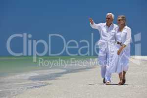 Happy Senior Couple Walking Pointing To Sea on Tropical Beach
