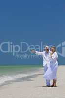 Happy Senior Couple Pointing To Sea on Tropical Beach