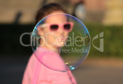 A girl looks through a bubble