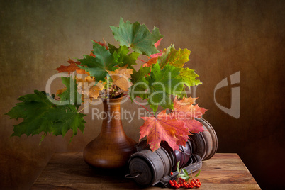 Herbstliches Stilleben mit Ahornblättern und Petroleumlampe
