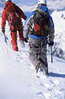 Young men mountain climbing on snowy peak