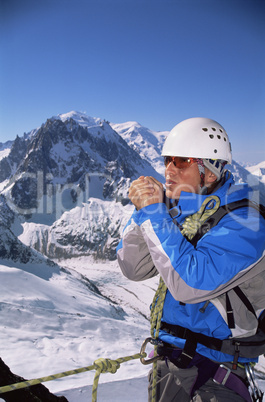 Young man warming hands on mountain peak