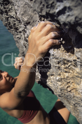 A young woman climbing up a rock face