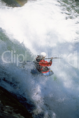 Young woman kayaking in rapids