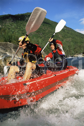 Two people paddling inflatable boat down rapids