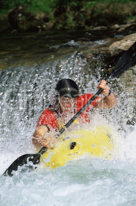 Young man kayaking in river