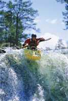 Young man kayaking on waterfall