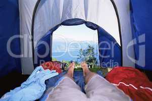Man lying in tent with a view of lake