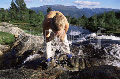 Young woman washing face in river