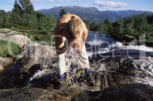 Young woman washing face in river