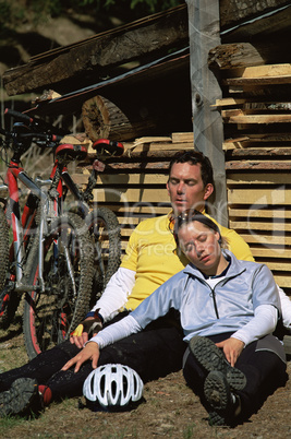 Exhuasted couple resting beside mountain bikes