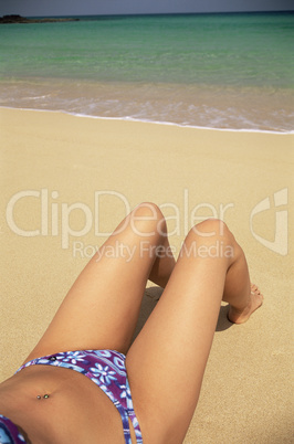 Low section of  woman sunbathing on beach