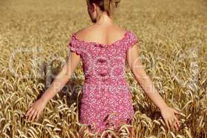 Rear view of young woman standing in wheatfield