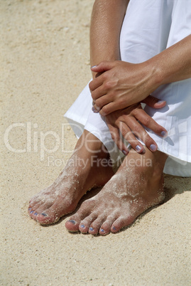 Young woman's feet covered in sand