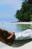 Midsection of man lying in hammock at beach