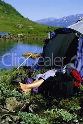 Young woman asleep in tent next to lake