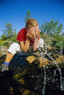 Young woman washing her face in river