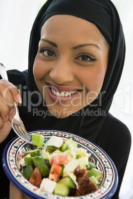 A Middle Eastern woman with a plate of salad