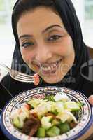 A Middle Eastern woman with a plate of salad