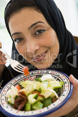 A Middle Eastern woman with a plate of salad