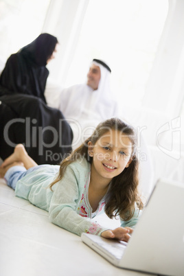 A Middle Eastern girl lying on the floor using a laptop