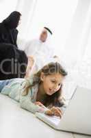 A Middle Eastern girl lying on the floor using a laptop