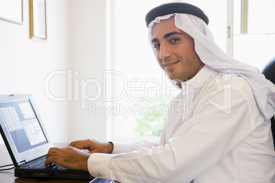 A Middle Eastern man sitting in front of a computer at home