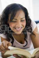 A Middle Eastern woman lying down reading