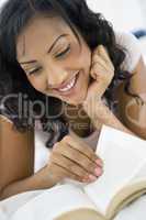 A Middle Eastern woman lying down reading