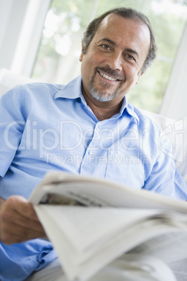 A Middle Eastern man reading a newspaper at home