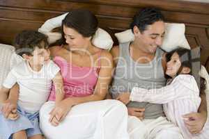 A Middle Eastern family lying on a bed
